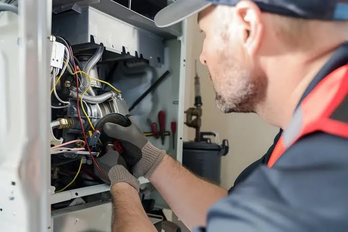 Technician testing wiring inside a residential furnace