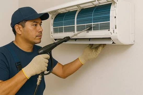 Technician cleaning a wall-mounted indoor cooling unit