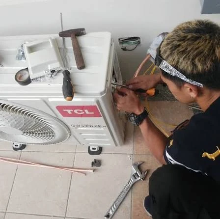 Technician servicing connections on an outdoor heating and cooling unit